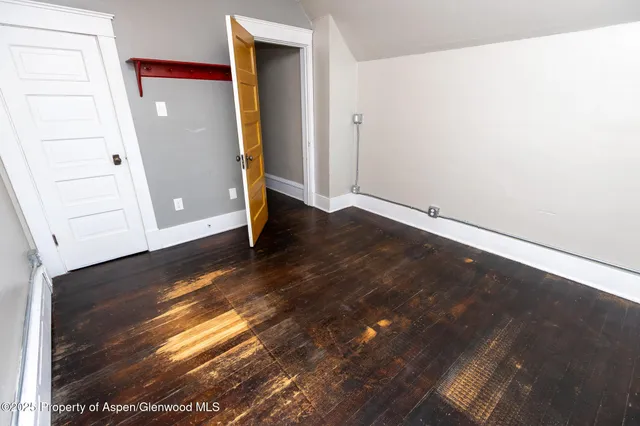 a view of an empty room with wooden floor and closet