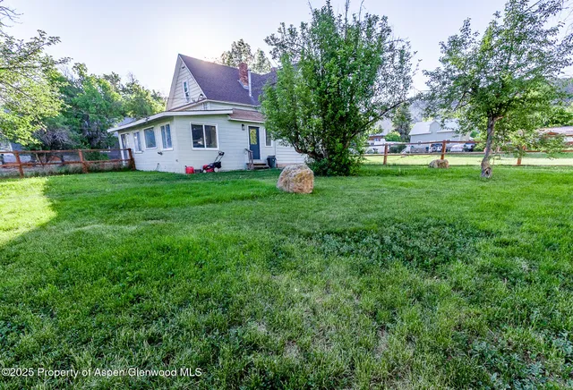 a view of a house with a big yard and large tree