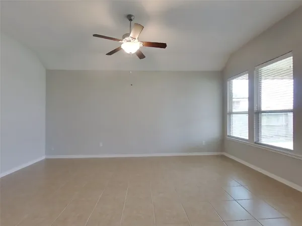 an empty room with windows and chandelier fan