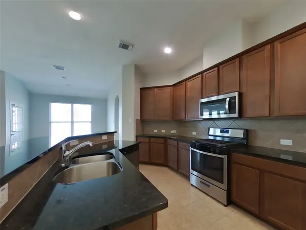 a kitchen with stainless steel appliances granite countertop a sink stove microwave and refrigerator