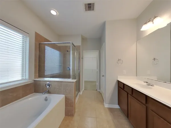 a spacious bathroom with a tub sink and mirror