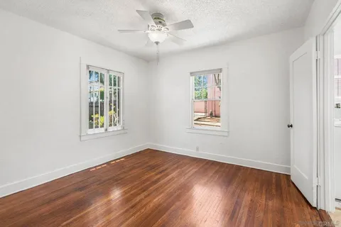 a view of an empty room with wooden floor and a window