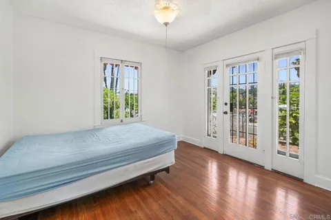 a spacious bedroom with a balcony a bed and wooden floor