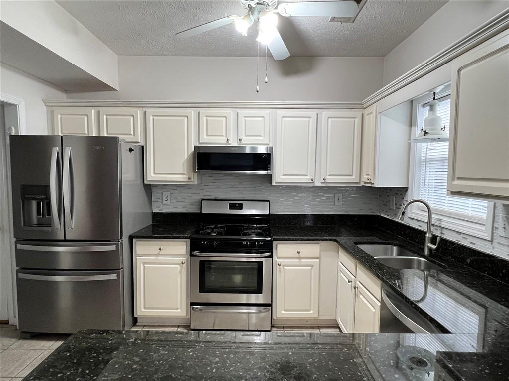5415 Taylor Road Alpharetta, GA 30022 - Photo 15 of 29 a kitchen with stainless steel appliances granite countertop a refrigerator a stove a sink and white cabinets