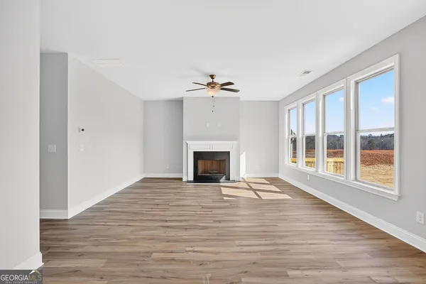 a view of an empty room with wooden floor fireplace and a window