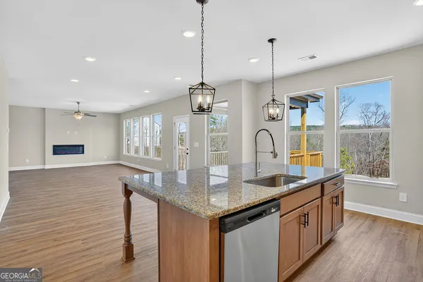 a kitchen with stainless steel appliances granite countertop wooden floors wooden cabinets a window and a sink