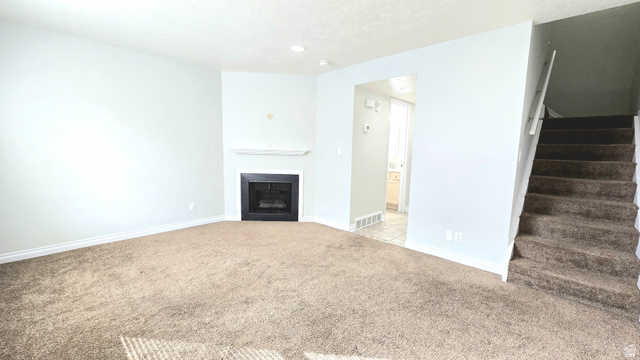 8732 Fairoaks Circle Sandy, UT 84070 - Photo 9 of 18 Unfurnished living room with light carpet and a fireplace