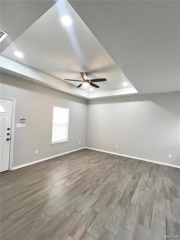 1635 Playa Drive, Unit 2 Weslaco, TX 78596 - Photo 12 of 17 an empty room with wooden floor chandelier fan and windows