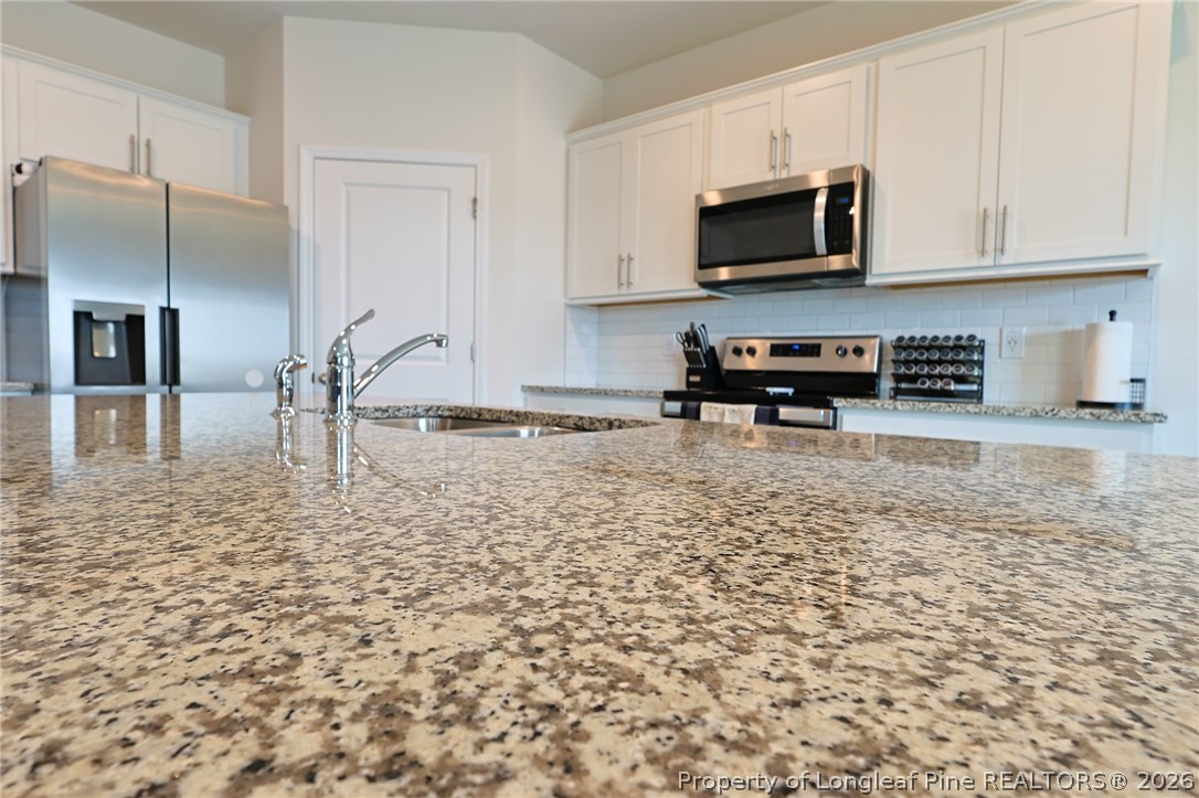 2129 Clydesmill Road Fayetteville, NC 28314 - Photo 7 of 36 a kitchen with granite countertop a stove a sink and a microwave