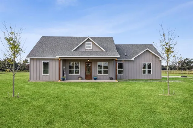 a front view of a house with a yard and trees