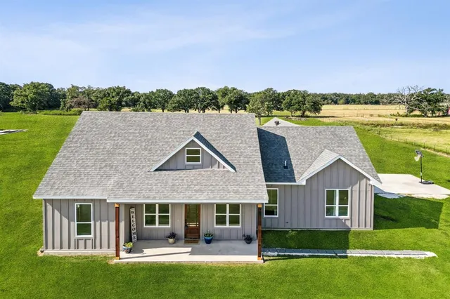 a front view of a house with a garden and lake view