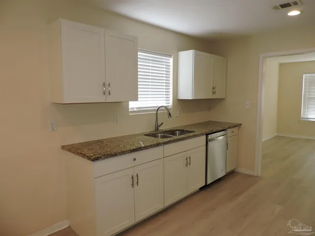 a kitchen with granite countertop white cabinets and a sink