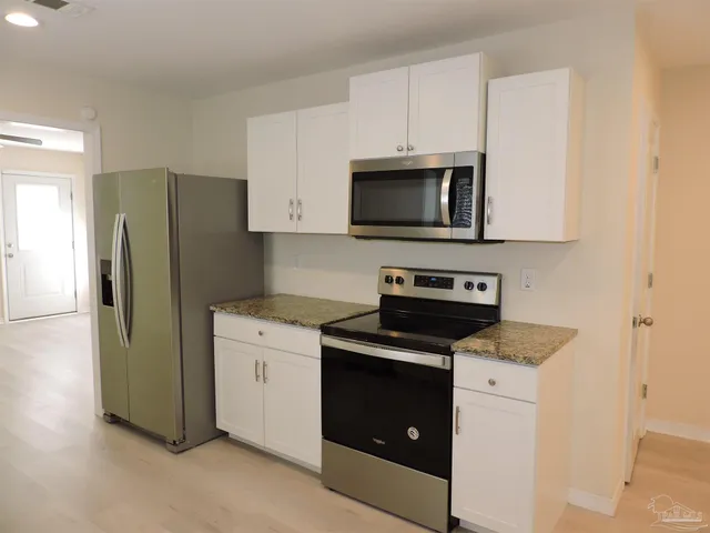 a kitchen with cabinets stainless steel appliances and wooden floor
