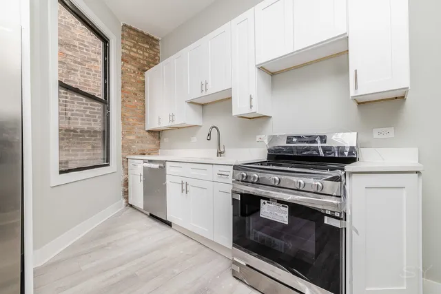 a kitchen with stainless steel appliances white cabinets and a stove top oven