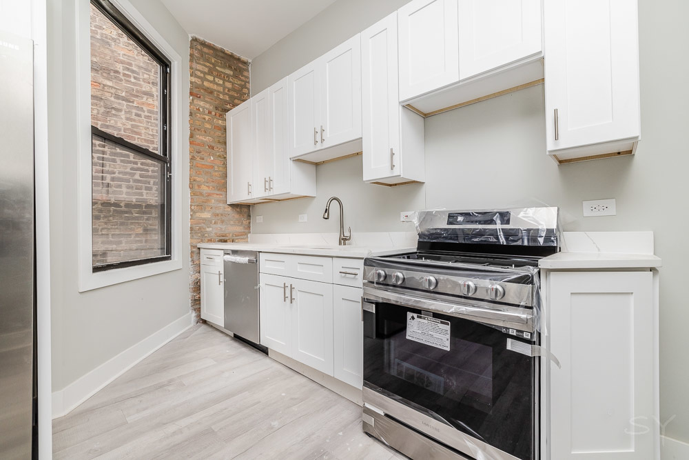 2448 South Oakley Avenue, Unit 2F Chicago, IL 60608 - Photo 3 of 14 a kitchen with stainless steel appliances white cabinets and a stove top oven