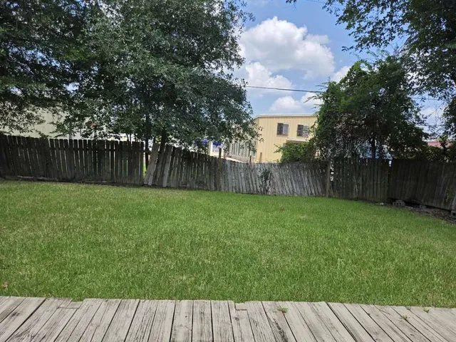 a view of backyard with wooden floor and fence