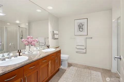 a bathroom with a granite countertop sink a large mirror a toilet and a shower