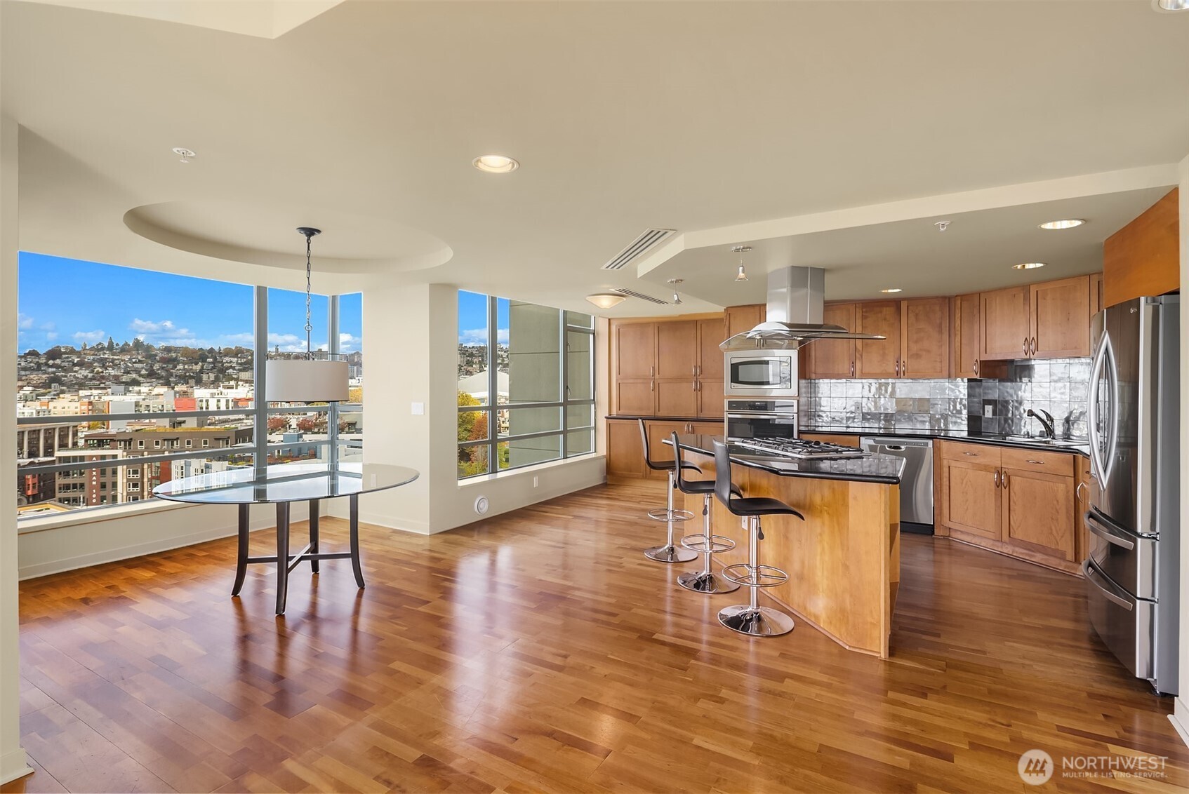 2929 1st Avenue, Unit 1200 Seattle, WA 98121 - Photo 7 of 23 a kitchen with stainless steel appliances wooden floor dining table and chairs
