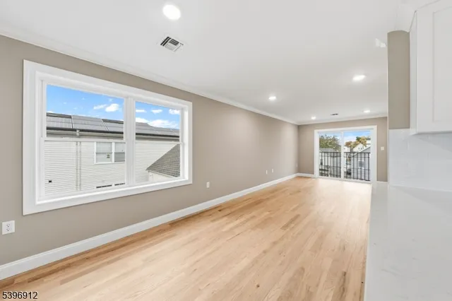 a view of an empty room with a window and wooden floor