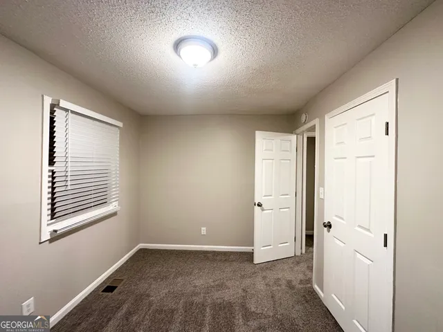 a view of an empty room with window and closet area