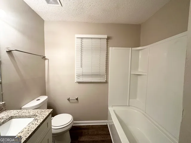 a bathroom with a granite countertop sink toilet and shower