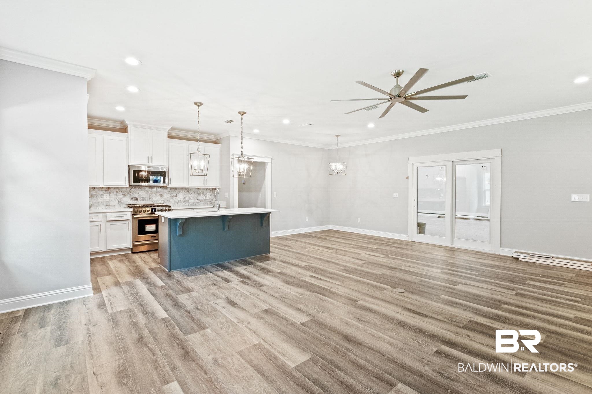 12441 Reunion Place Foley, AL 36535 - Photo 7 of 31 Kitchen with a breakfast bar area, stainless steel appliances, an island with sink, light hardwood / wood-style flooring, and white cabinets