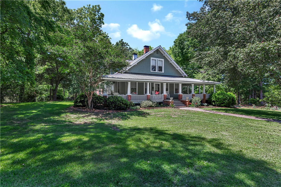 205 West Mauldin Street Walhalla, SC 29691 - Photo 35 of 43 Timeless charm radiates from this inviting home, framed by lush foliage and a welcoming wrap-around porch.