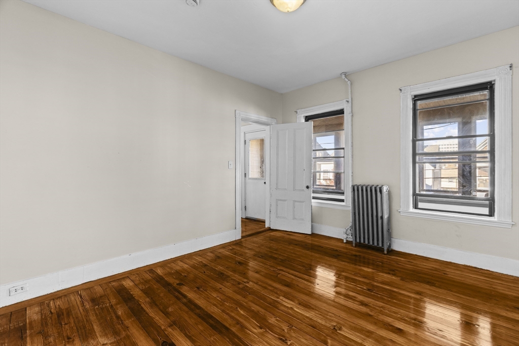 15-17 Cushman Road Boston, MA 02135 - Photo 13 of 27 an empty room with wooden floor and windows