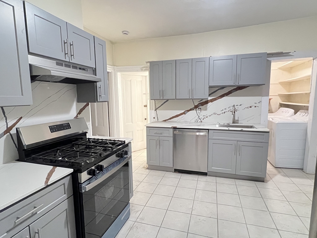 15-17 Cushman Road Boston, MA 02135 - Photo 4 of 27 a kitchen with a stove a sink and cabinets