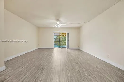 an empty room with wooden floor chandelier fan and windows