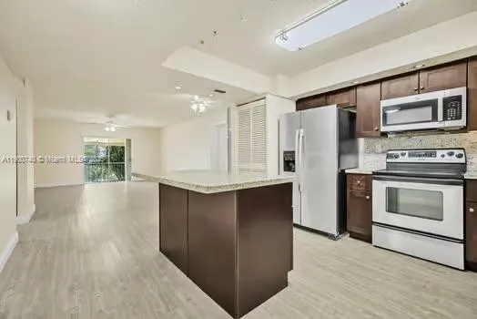 a kitchen with stainless steel appliances kitchen island wooden cabinets and granite counter tops