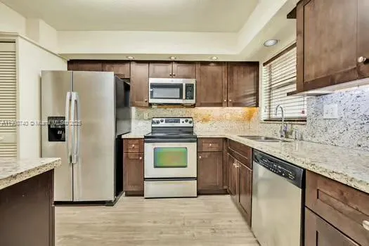 a kitchen with stainless steel appliances granite countertop a refrigerator stove a sink and dishwasher