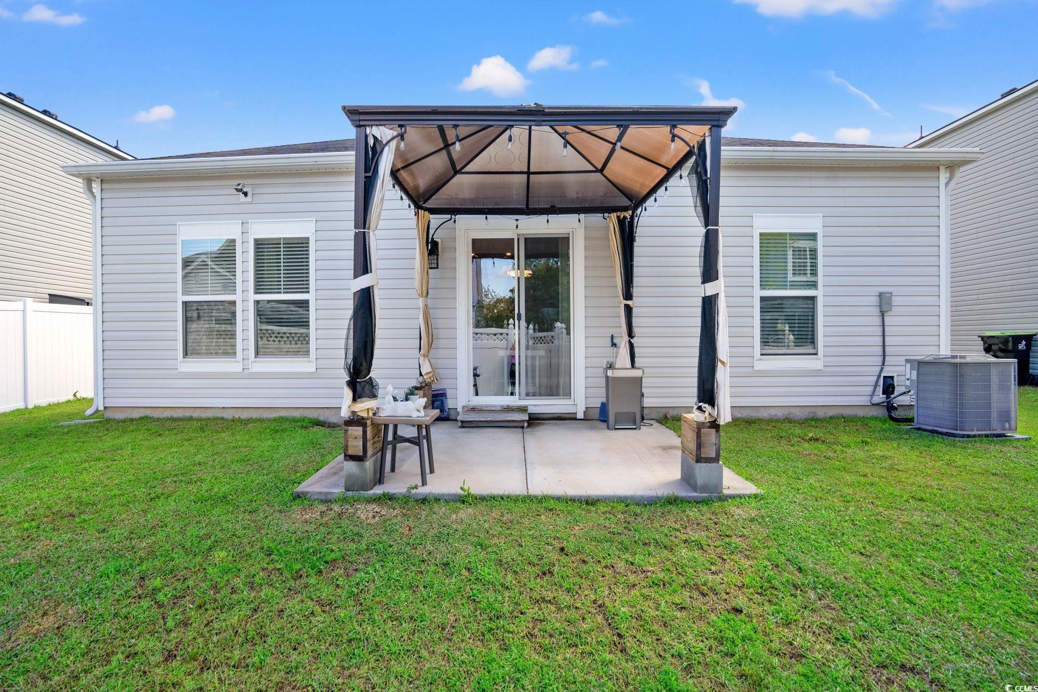 155 Marsh Deer Place Surfside Beach, SC 29575 - Photo 22 of 35 Rear view of property featuring a lawn, a patio area, fence, and central AC