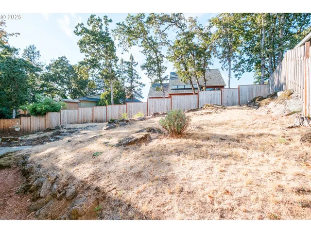 a backyard of a house with a large tree and wooden fence
