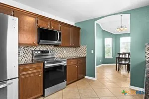 a kitchen with stainless steel appliances granite countertop a stove top oven a sink dishwasher a dining table and chairs with wooden floor