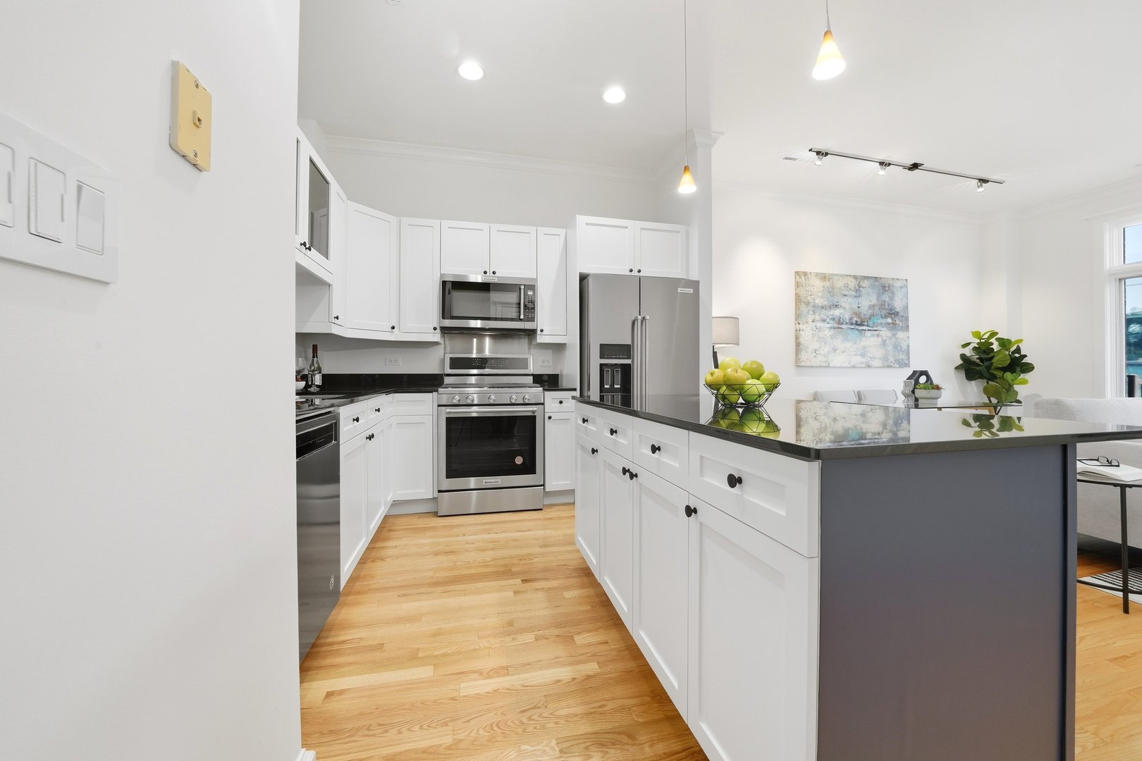 800 West Cornelia Avenue, Unit 307 Chicago, IL 60657 - Photo 16 of 22 a large white kitchen with stainless steel appliances kitchen island granite countertop a sink counter space and cabinets