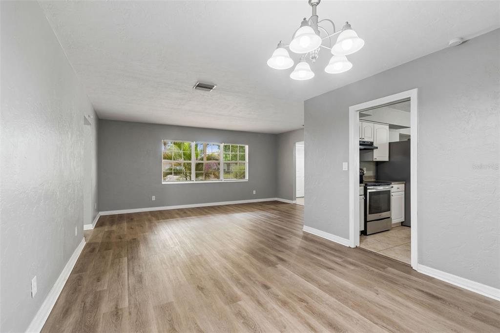 9931 110th Street Seminole, FL 33772 - Photo 12 of 52 an empty room with wooden floor chandelier and windows