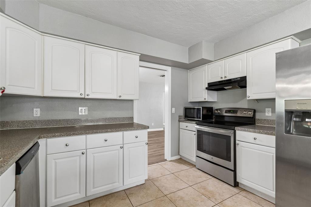 9931 110th Street Seminole, FL 33772 - Photo 16 of 52 a kitchen with granite countertop white cabinets and stainless steel appliances