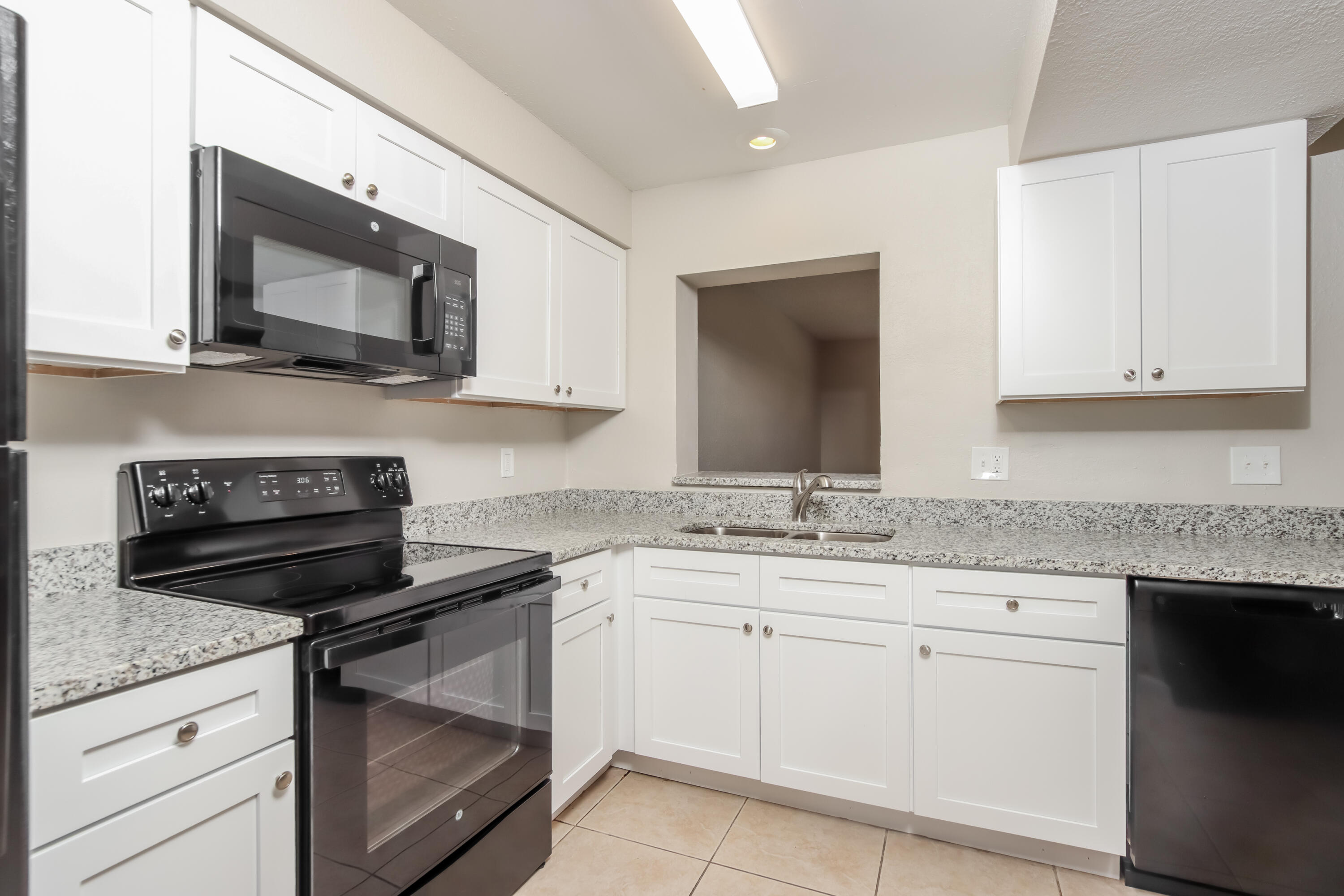 1195 Cotton Road Northeast Palm Bay, FL 32905 - Photo 7 of 17 a kitchen with white cabinets and black appliances