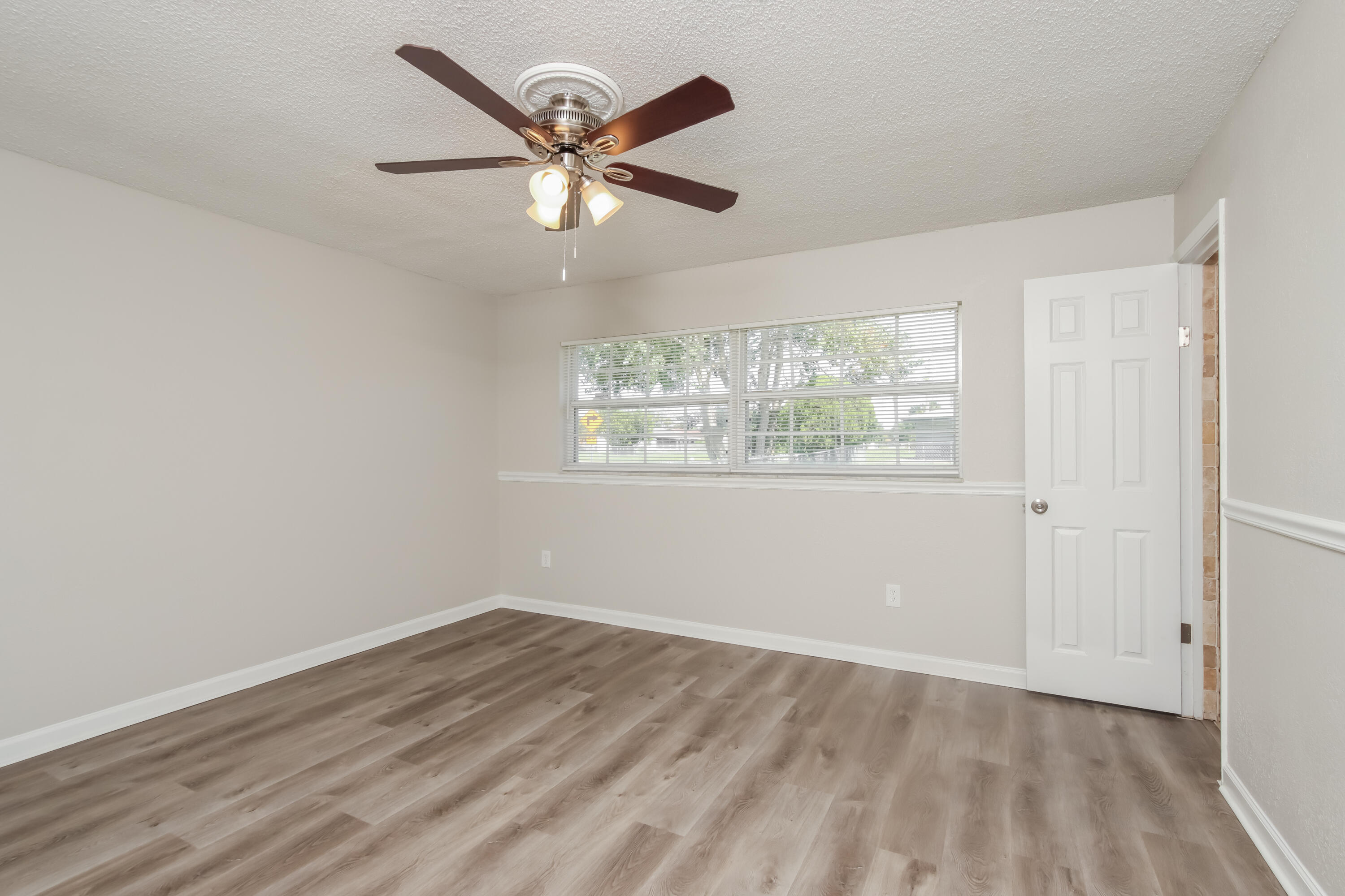 1195 Cotton Road Northeast Palm Bay, FL 32905 - Photo 9 of 17 an empty room with wooden floor fan and windows