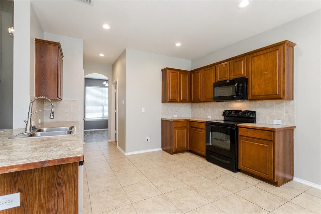 203 Arabian Road Waxahachie, TX 75165 - Photo 4 of 24 Kitchen featuring wood cabinetry, stone-finish countertops, tile flooring, black appliances, and recessed lighting