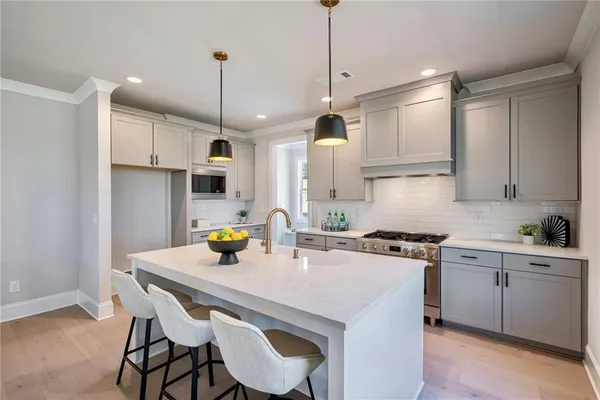 a kitchen with stainless steel appliances granite countertop a sink a stove a refrigerator and island with wooden floor