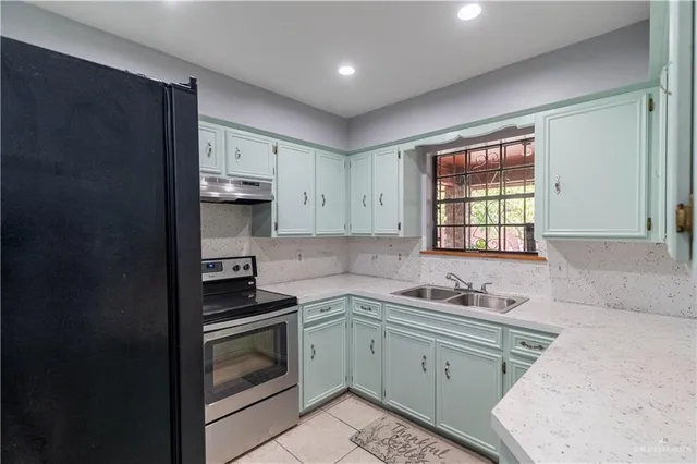 a kitchen with granite countertop a sink cabinets stainless steel appliances and a window
