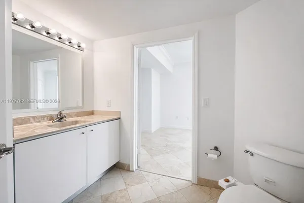 a en suite bathroom with a granite countertop sink mirror and toilet