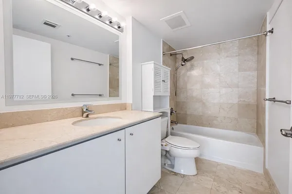 a bathroom with a granite countertop sink a toilet and a large mirror