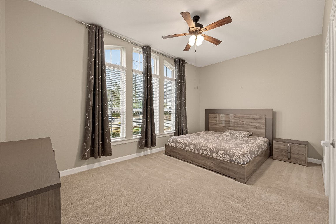 2706 Ripe Amber Cup Court Richmond, TX 77406 - Photo 25 of 50 a bedroom with a large bed and a chandelier