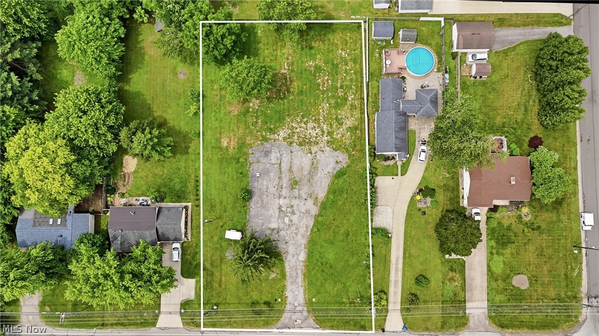 7474 Avon Belden Road North Ridgeville, OH 44039 - Photo 2 of 6 Expansive, level land parcel featuring mature trees, a partially paved surface, and direct road frontage