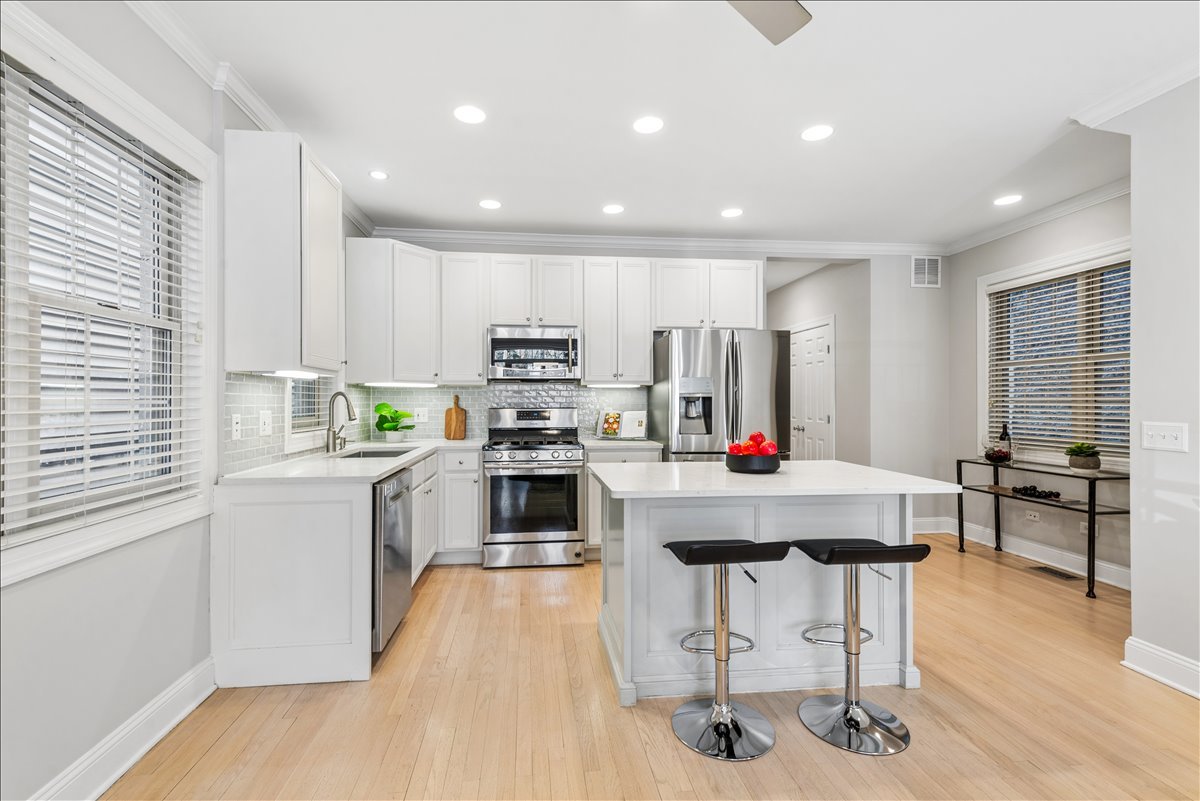 2838 North Damen Avenue, Unit 1 Chicago, IL 60618 - Photo 6 of 25 a kitchen with kitchen island granite countertop stainless steel appliances cabinets a dining table and a window