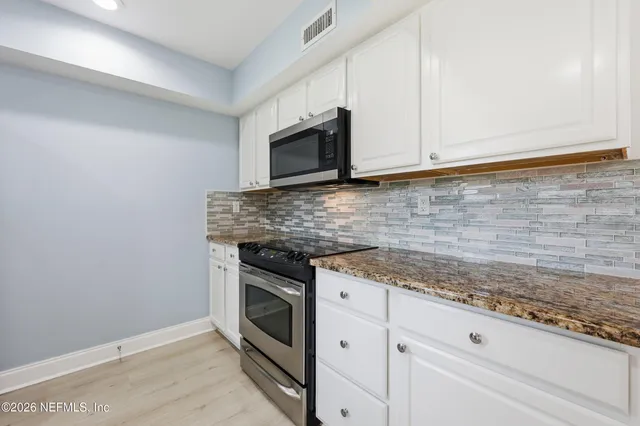 a kitchen with granite countertop white cabinets stainless steel appliances and a sink