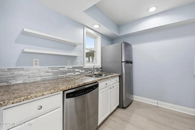 a kitchen with stainless steel appliances granite countertop a sink and a refrigerator